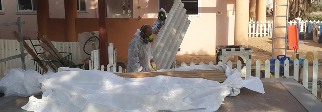 צוות מקצועי לפינוי אסבסט לובש ציוד מגן בזמן עבודה על גג.