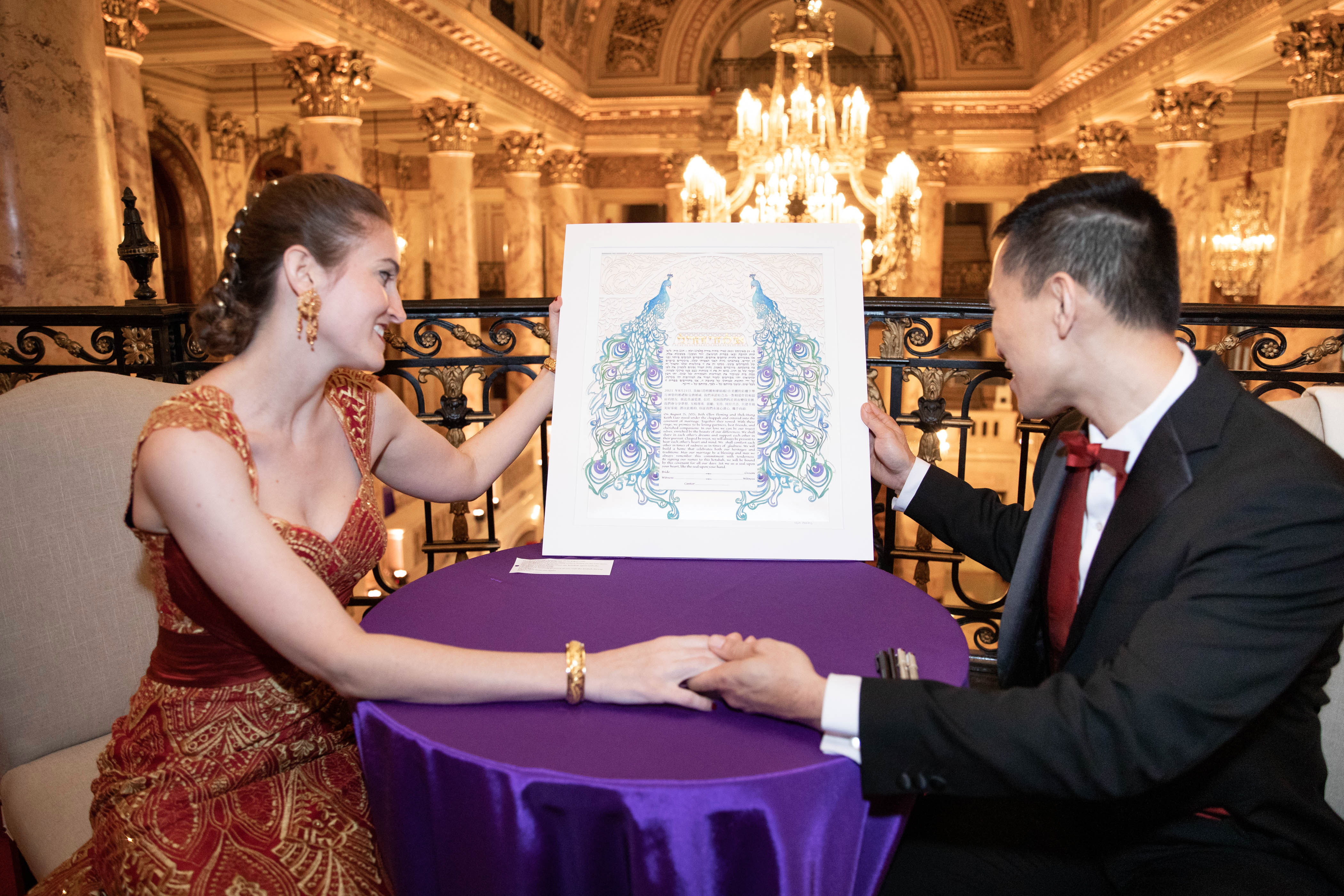 A photo of a young couple holding their newly signed Ketubah, looking towards the future.